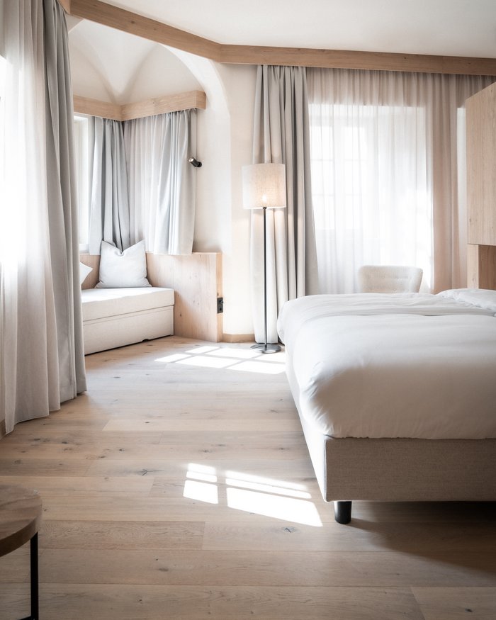 Camera da letto luminosa con pavimento in legno, letto e poltrona