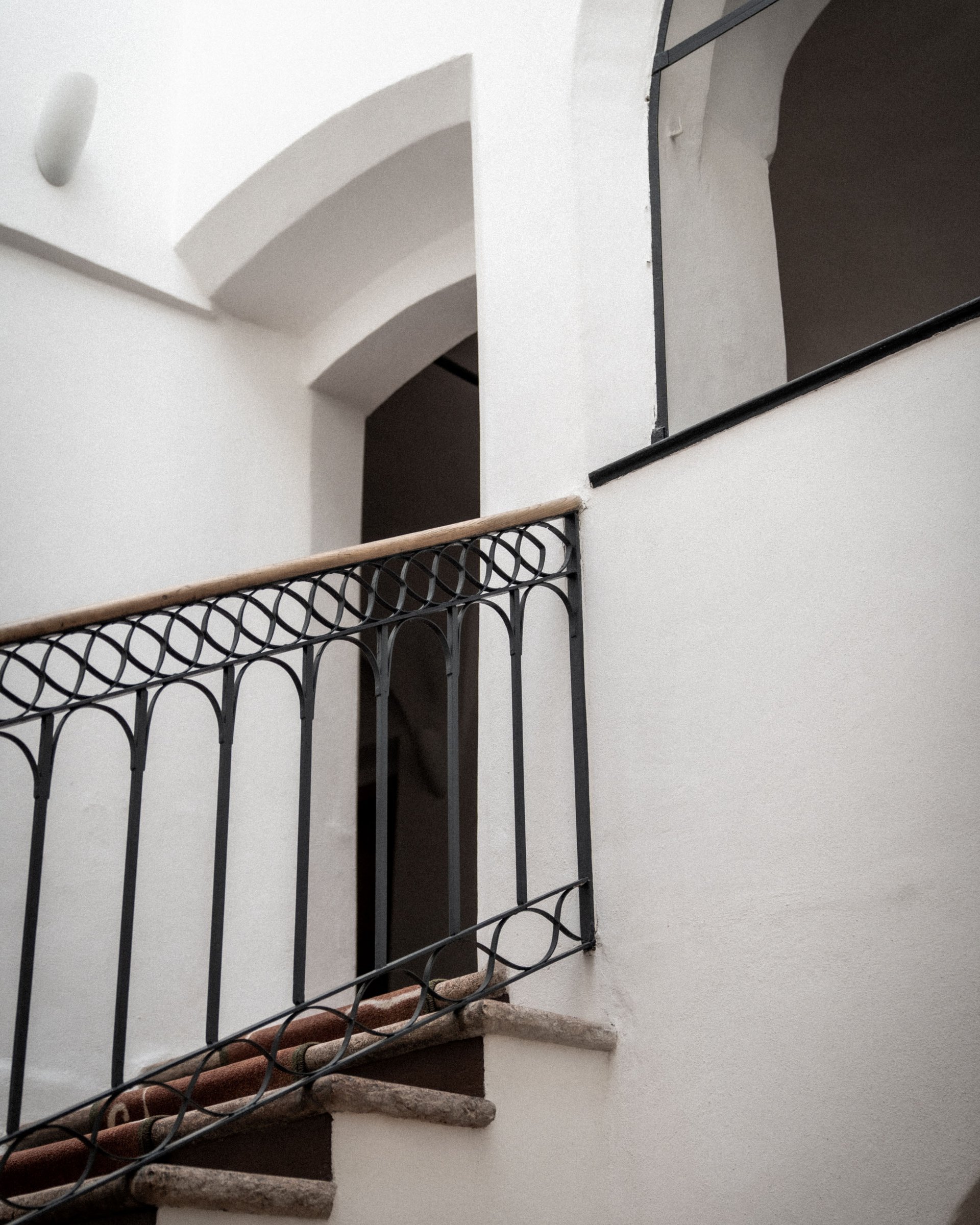 Scala interna con ringhiera in ferro battuto e corrimano in legno