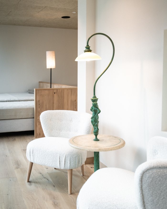 Stanza luminosa con due poltrone bianche, piccolo tavolo e lampada