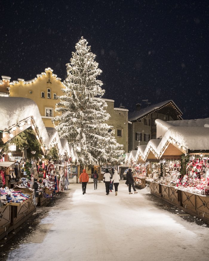 Mercatino di Natale di notte con albero decorato e neve