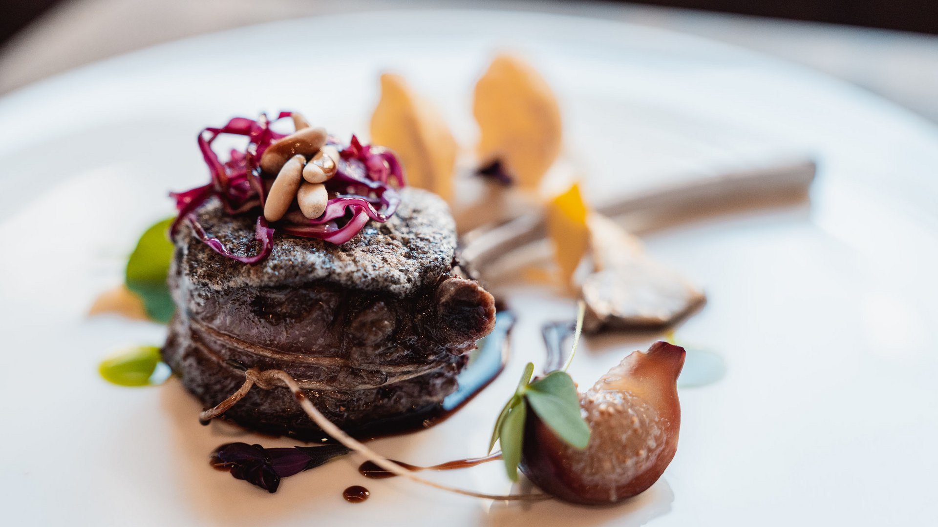 Bistecca gourmet con pinoli e cavolo rosso su piatto bianco, presentazione artistica