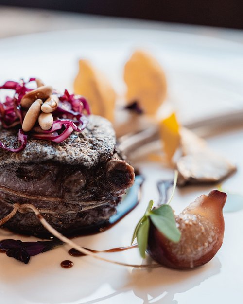 Bistecca gourmet con pinoli e cavolo rosso su piatto bianco, presentazione artistica