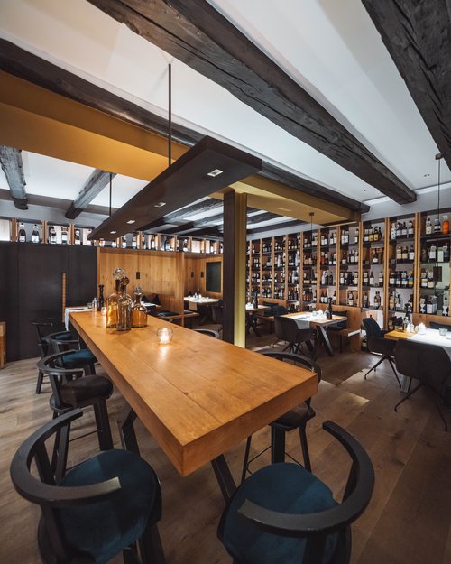 Ristorante moderno con tavoli in legno e pareti piene di bottiglie di vino