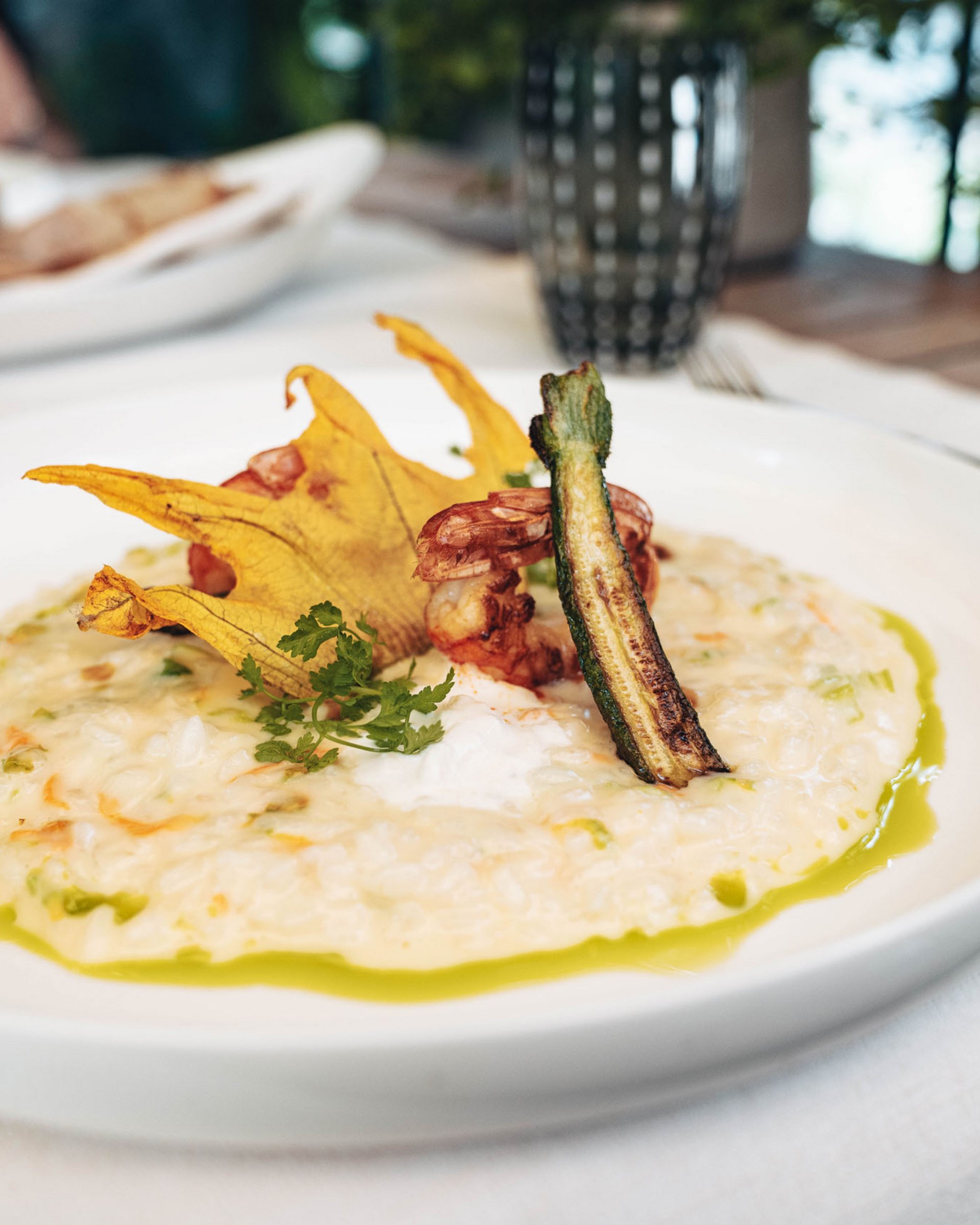 Un piatto di risotto cremoso guarnito con zucchine, gamberi e fiori commestibili