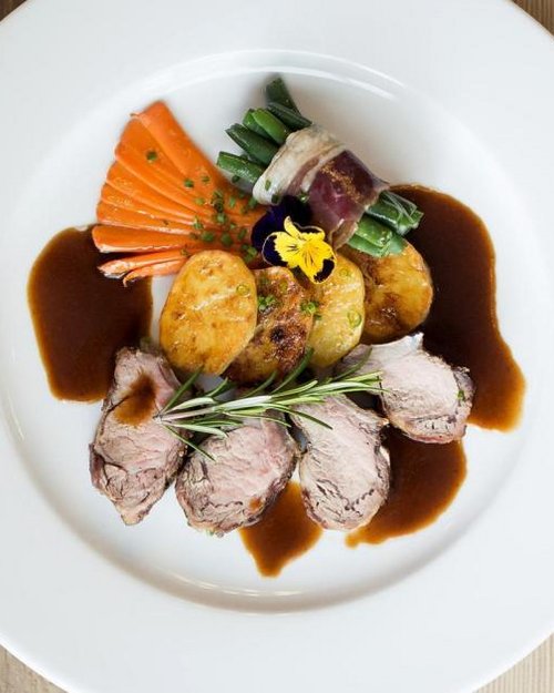 Piatto gourmet con carne, patate, verdure verdi e salsa su piatto bianco