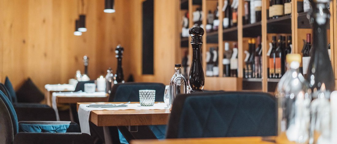 Ristorante accogliente con mensole per vini e tavoli di legno apparecchiati