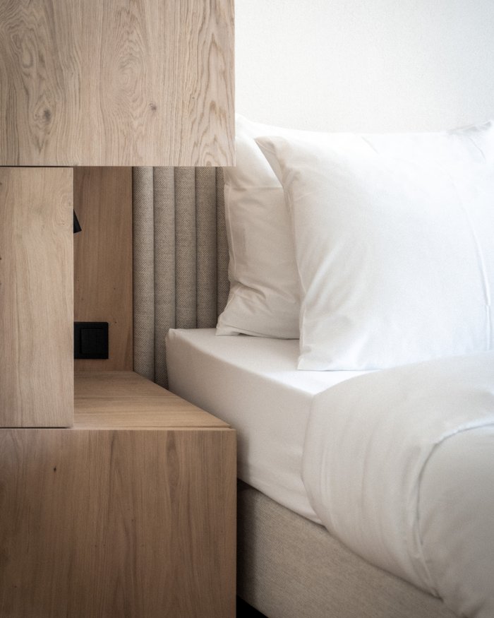 Comodino in legno accanto a letto bianco con cuscini in camera moderna