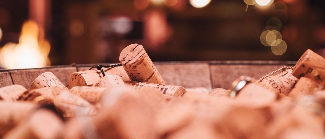 Primo piano di molti tappi di sughero di bottiglie di vino in un contenitore con sfondo sfocato