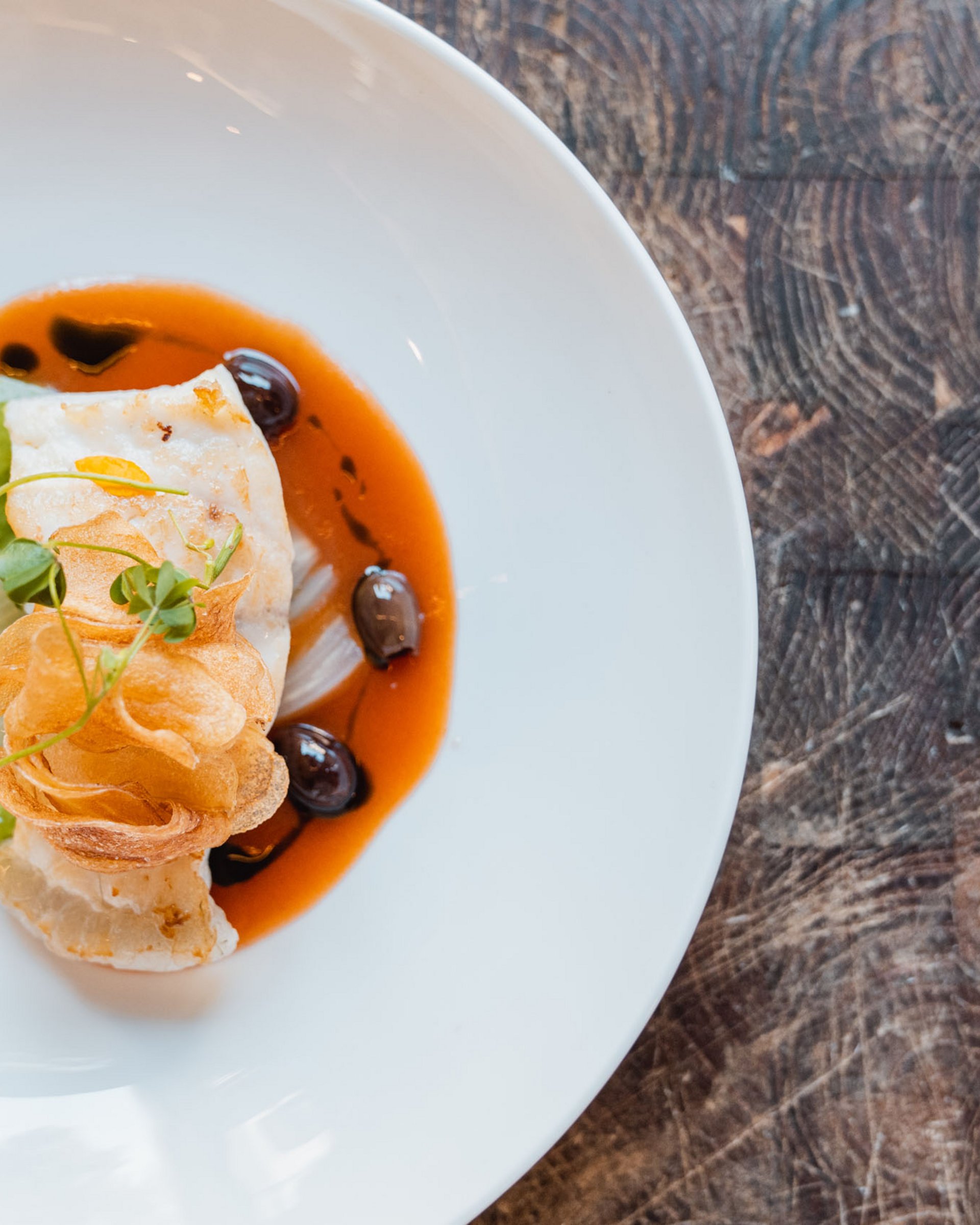 Piatto di pesce decorato con salse verde e rossa su piatto bianco