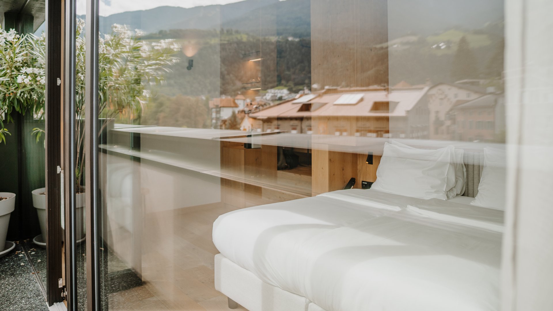 Vista attraverso il vetro di un letto chiaro in una stanza con vista montagne