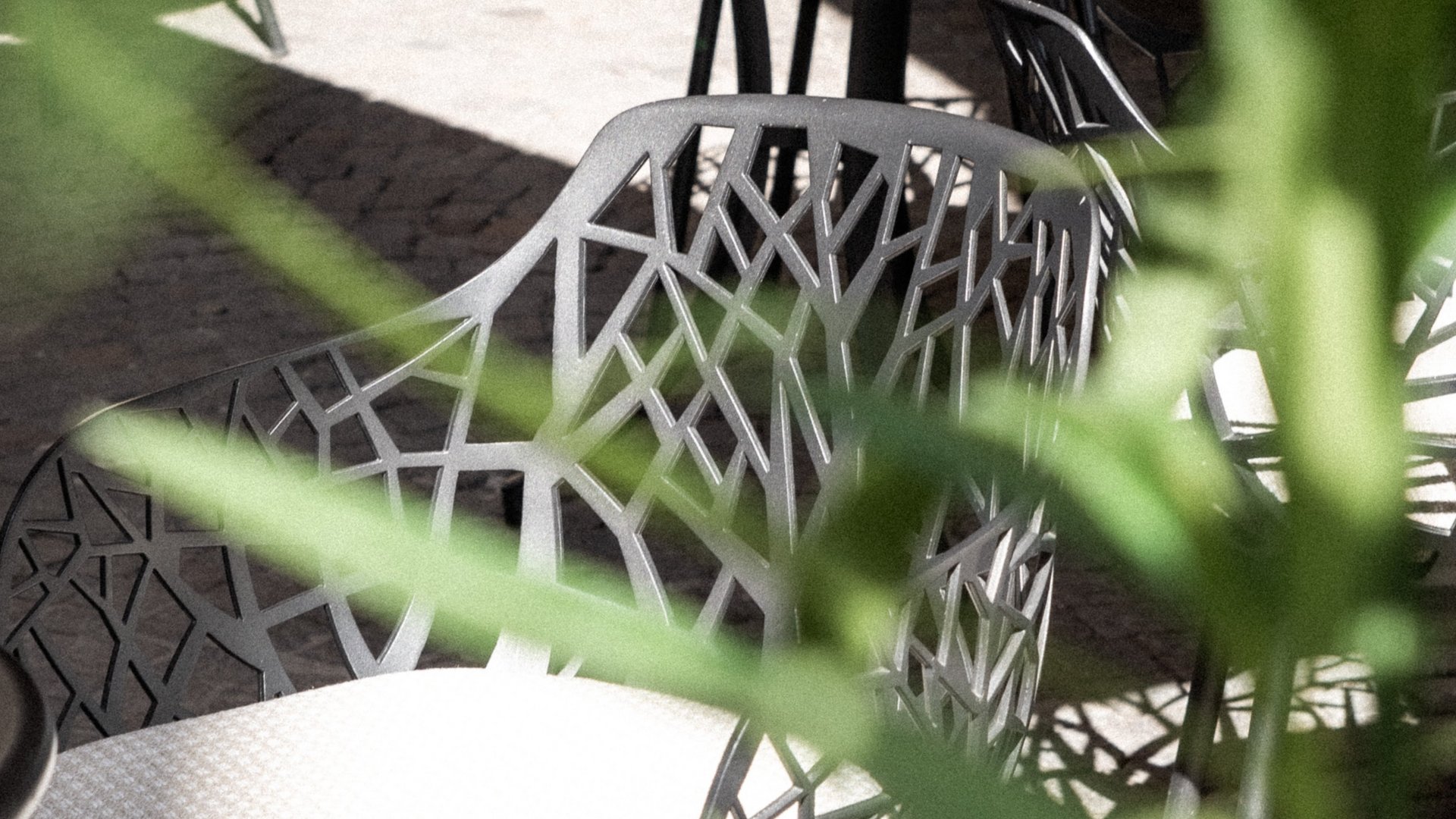 Sedie moderne da esterno con design traforato e cuscino chiaro in un cortile