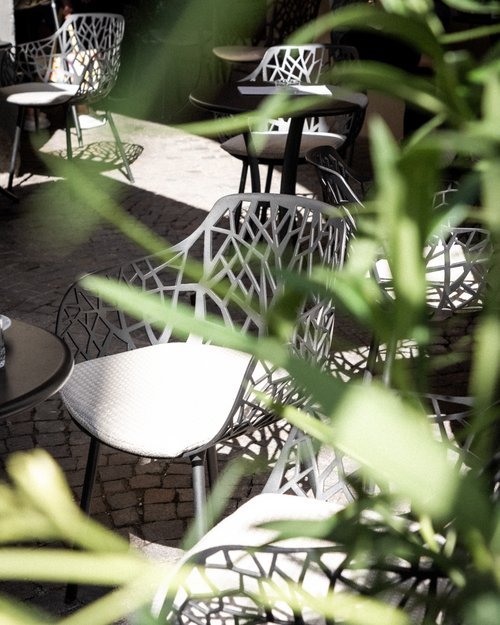 Sedie moderne da esterno con design traforato e cuscino chiaro in un cortile