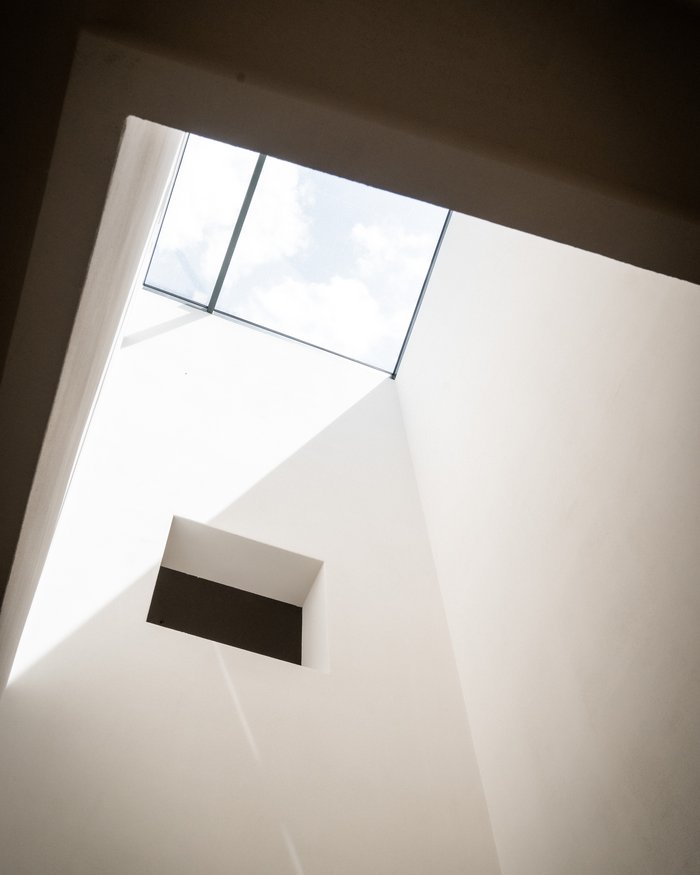 Vista verso l'alto di una finestra a soffitto quadrata e pareti bianche interne