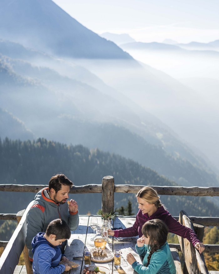 Famiglia che mangia all'aperto con vista sulle montagne in giornata limpida