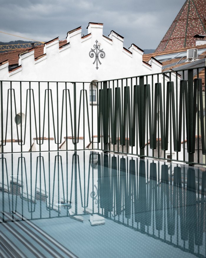 Riflessione di una ringhiera su una superficie in vetro con edificio storico sullo sfondo