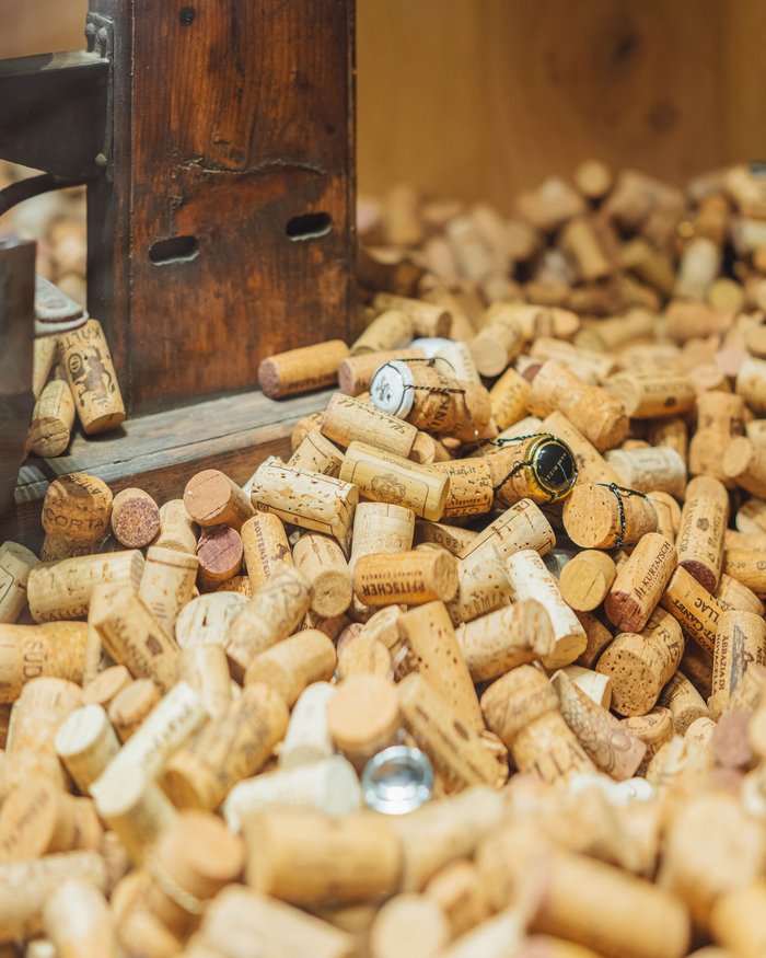 Molti tappi di sughero per vino davanti a un pannello di legno