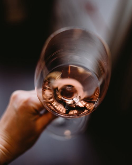 Mano che tiene un bicchiere di vino rosato