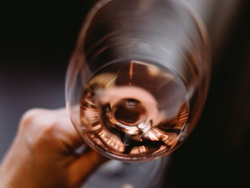 Mano che tiene un bicchiere di vino rosato