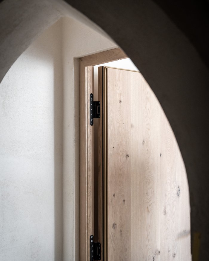 Porta in legno leggermente aperta con cornice ad arco in pietra