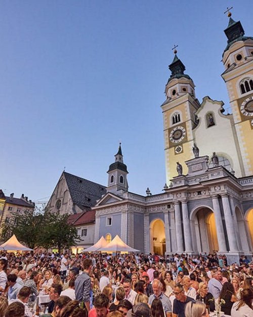Folla a un festival davanti a una chiesa con due torri al tramonto