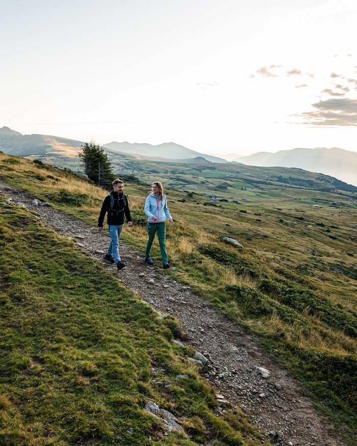 Due escursionisti su sentiero di montagna all'alba con paesaggio e montagne