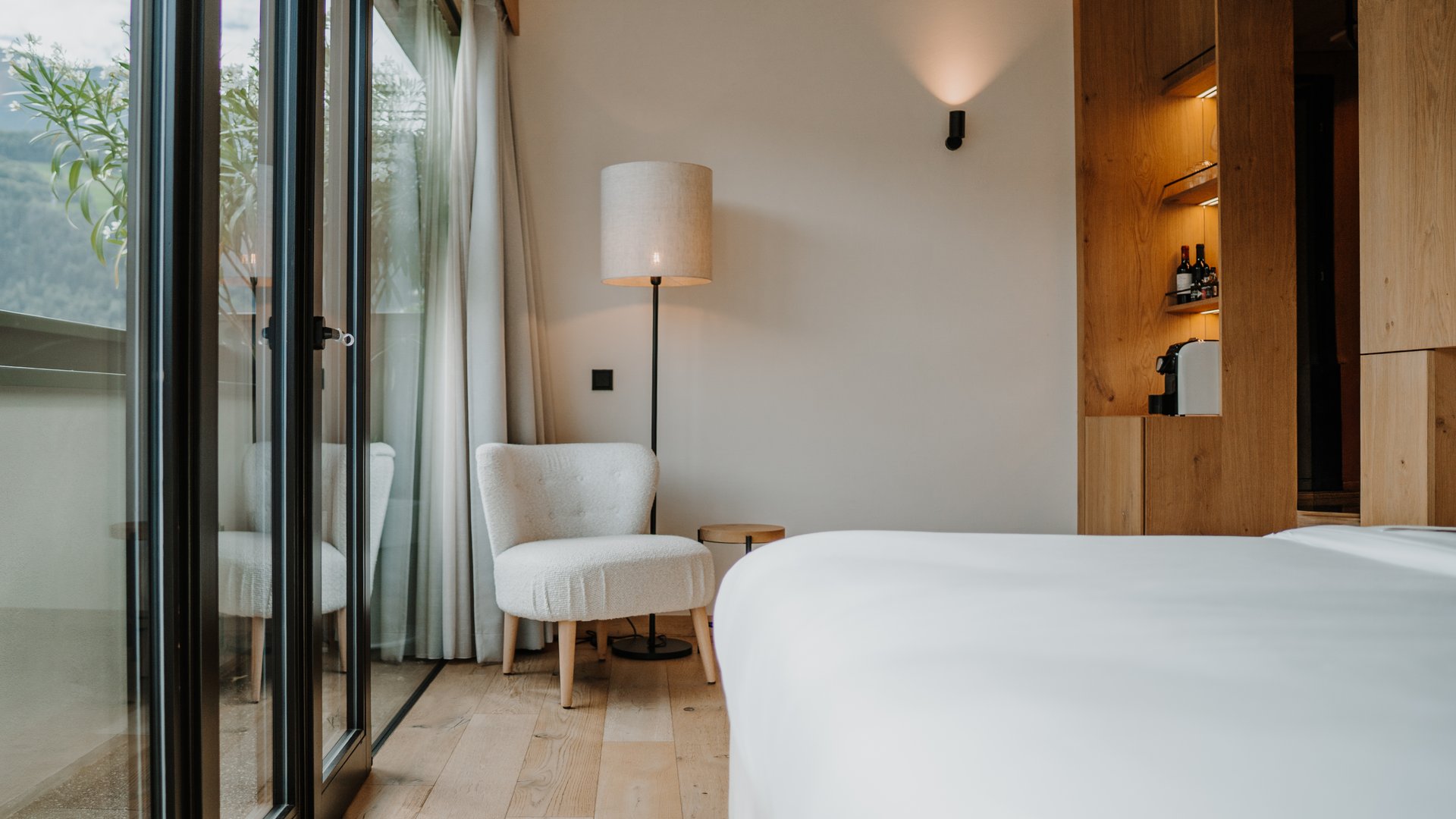 Sedia accogliente accanto a lampada da terra e letto in camera d'hotel moderna