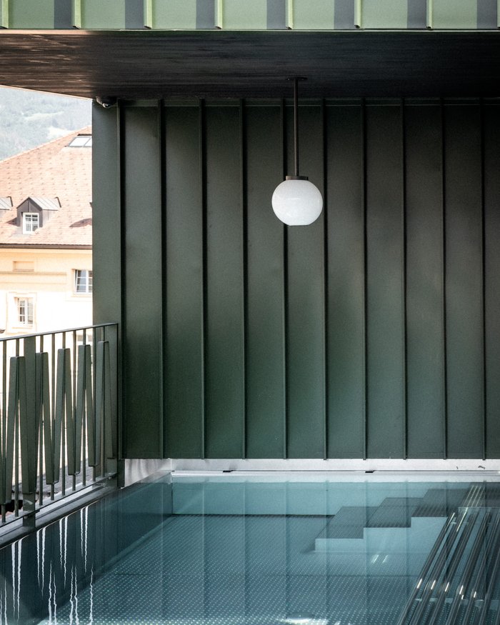 Piscina moderna con pareti in vetro e lampada rotonda in stanza verde