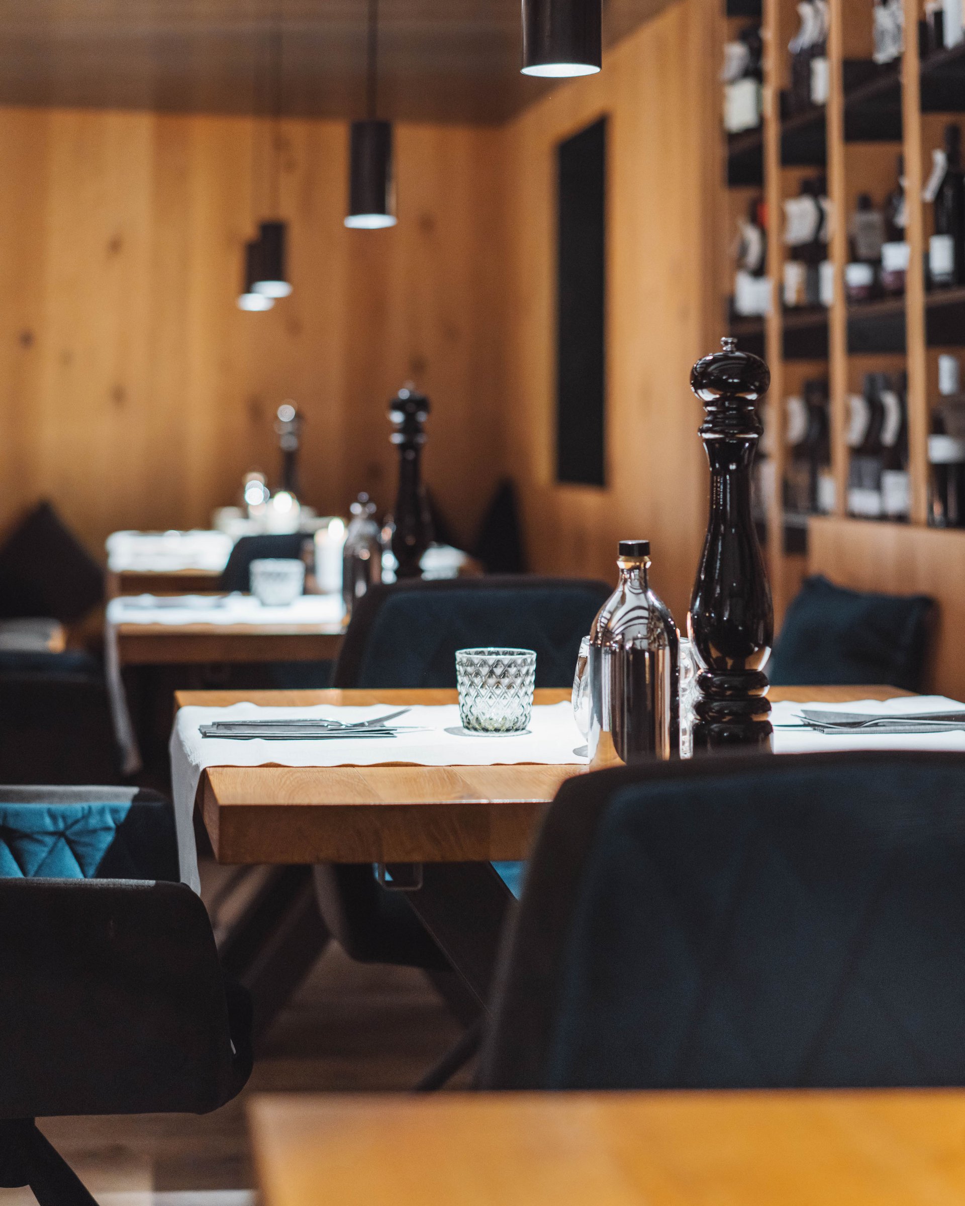 Ristorante con tavoli in legno, sedie scure e set da tavola con macinapepe