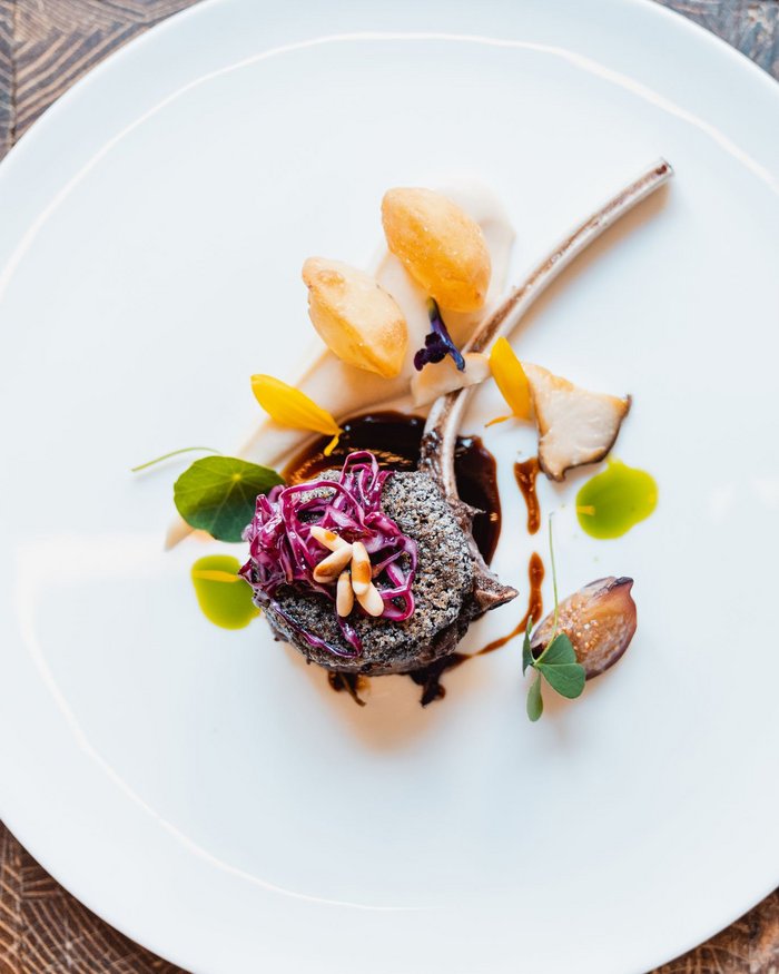 Piatto gourmet elegantemente impiattato con costolette di agnello e guarnizioni colorate