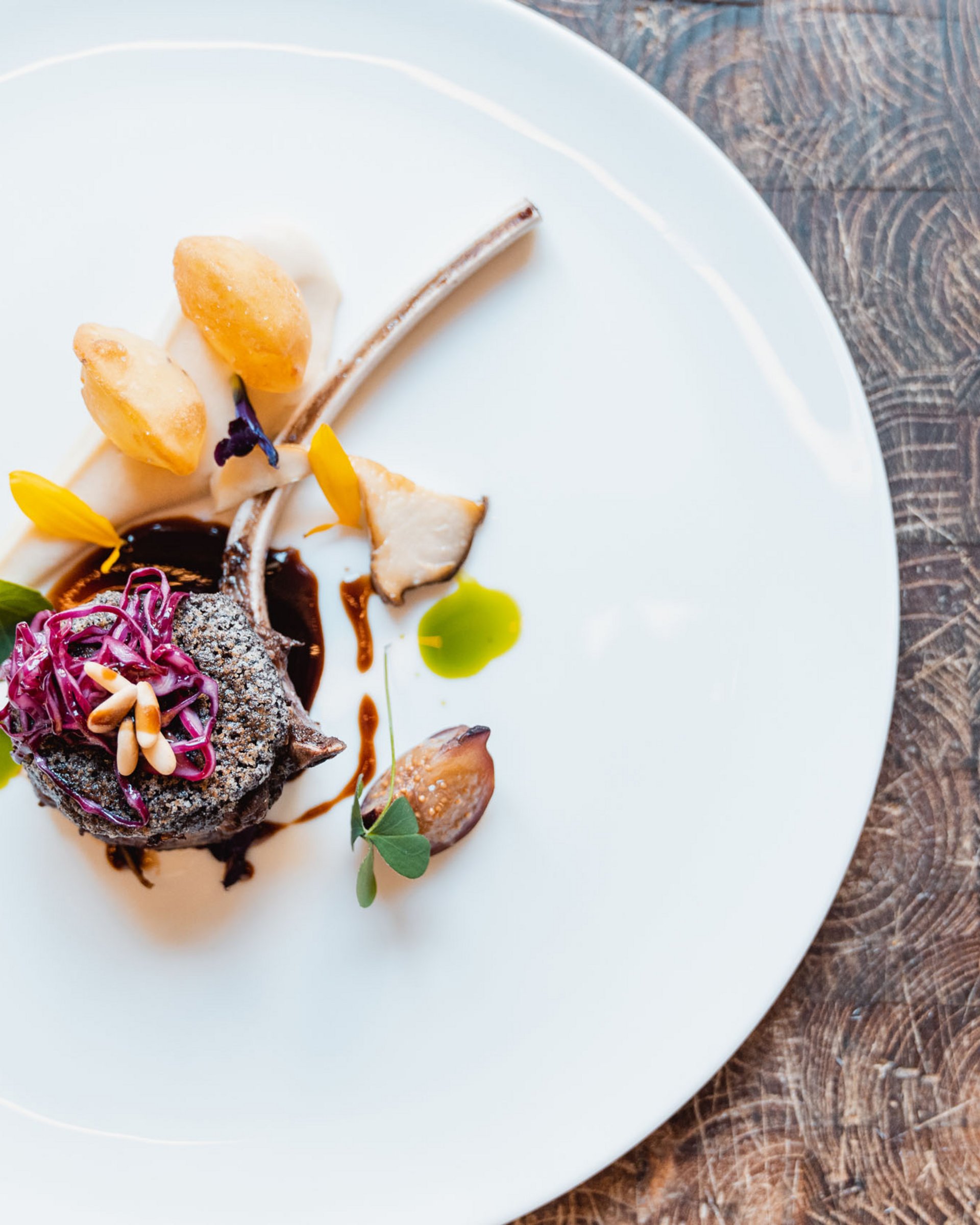 Piatto gourmet elegantemente impiattato con costolette di agnello e guarnizioni colorate