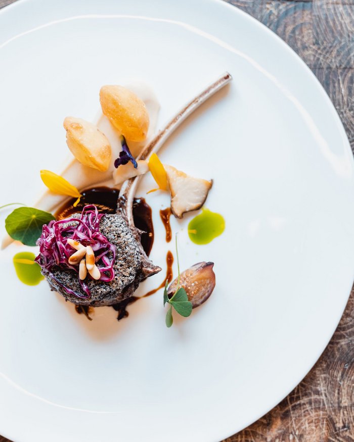 Piatto gourmet elegantemente impiattato con costolette di agnello e guarnizioni colorate