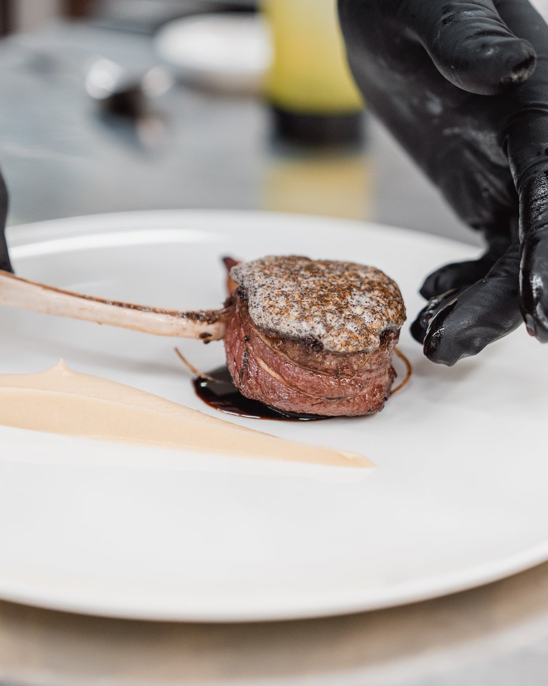 Piatto gourmet con carne e crema impiattato su piatto bianco