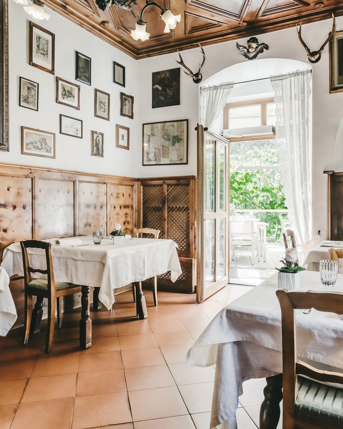 Ristorante accogliente con mobili in legno, tovaglie bianche e opere d'arte alle pareti