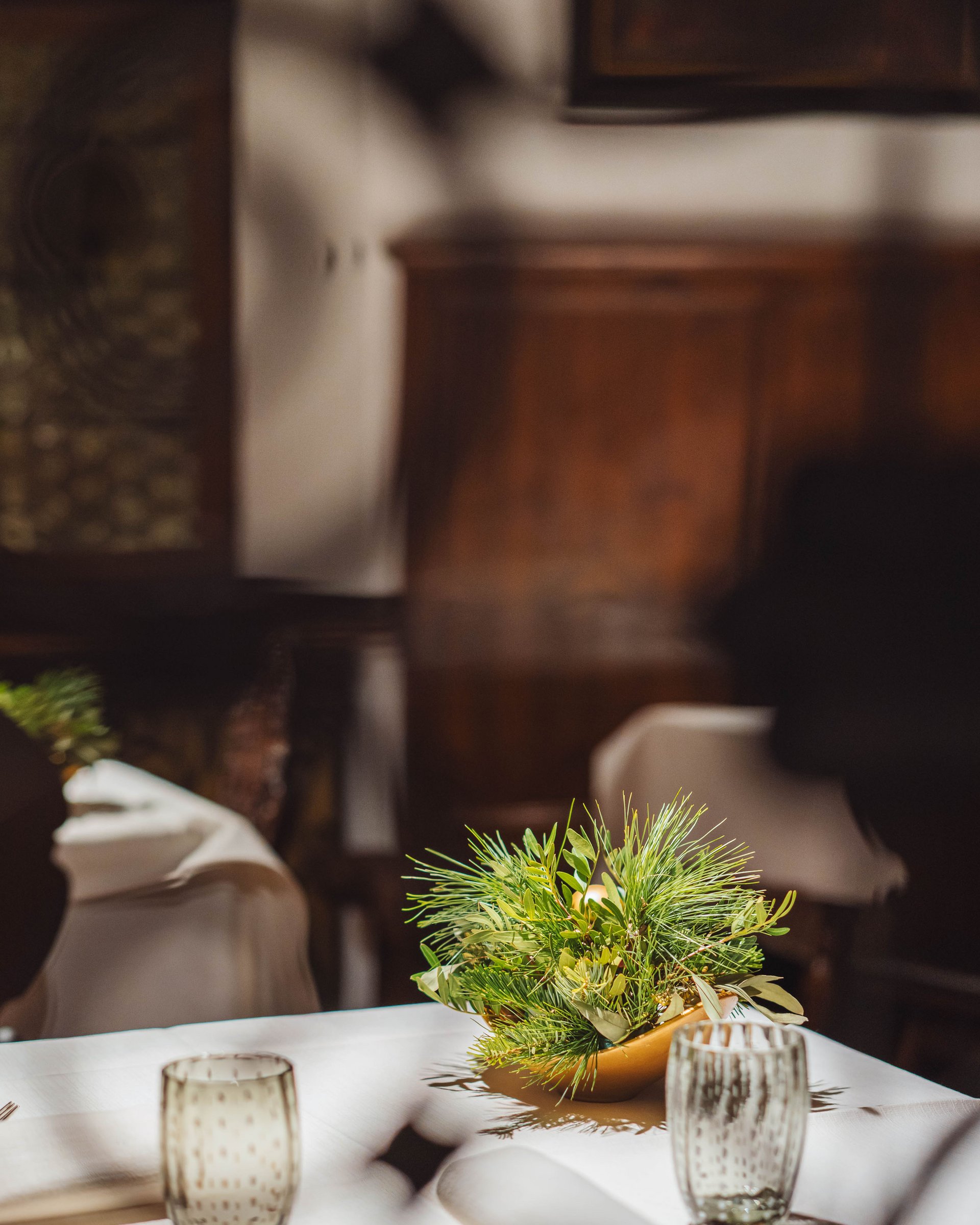 Tavolo con tovaglia, bicchiere, posate e decorazione floreale verde