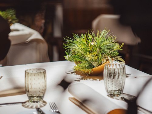 Tavolo con tovaglia, bicchiere, posate e decorazione floreale verde