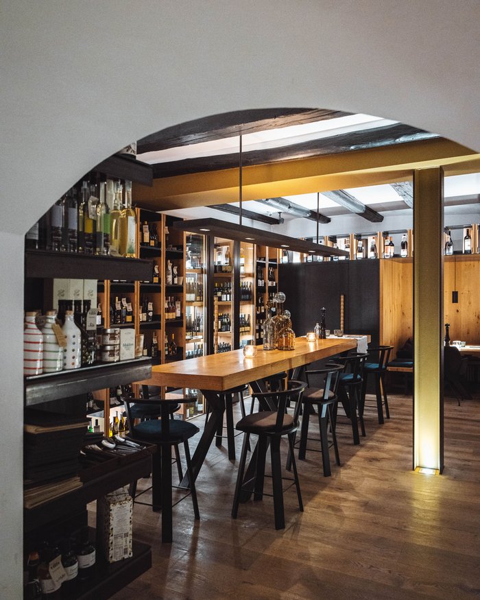 Area bar accogliente con bancone in legno, sedie e scaffali pieni di bottiglie