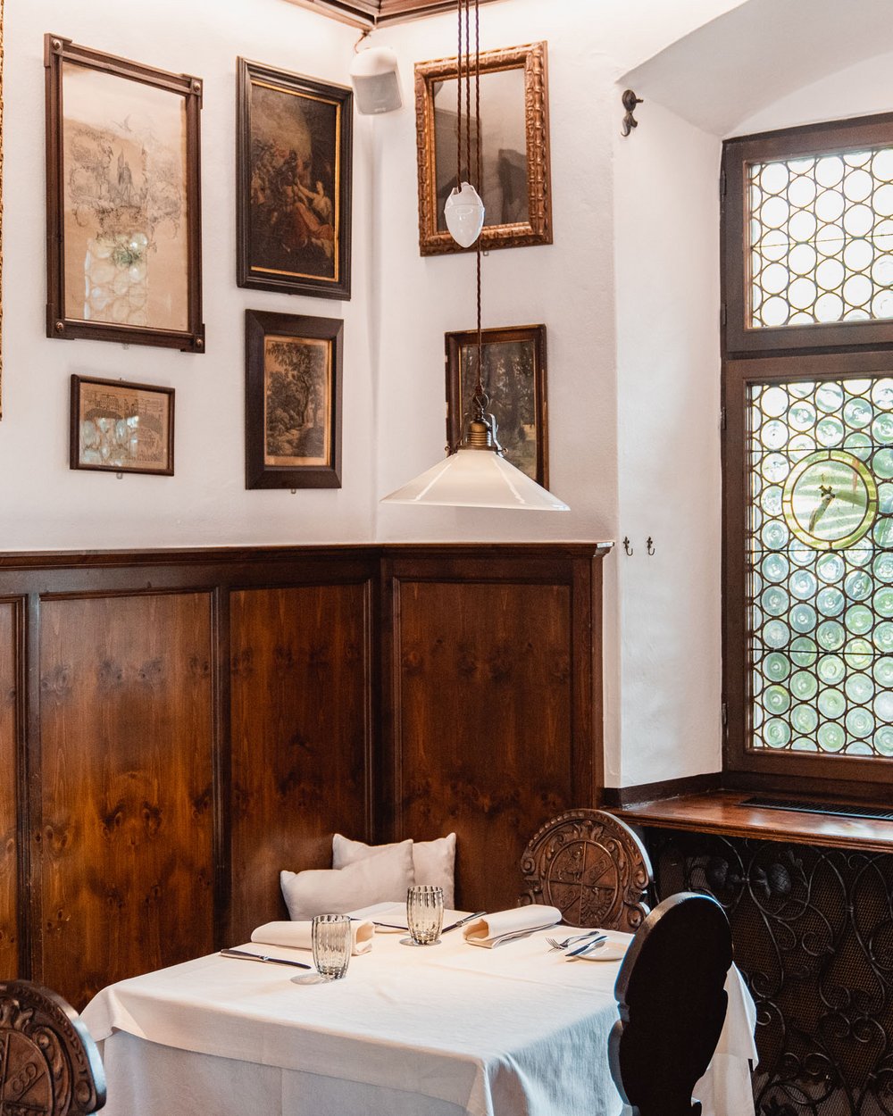 Angolo pranzo accogliente con pareti in legno, quadri e finestra colorata