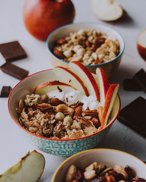 Ciotola con muesli, noci, fette di mela e yogurt