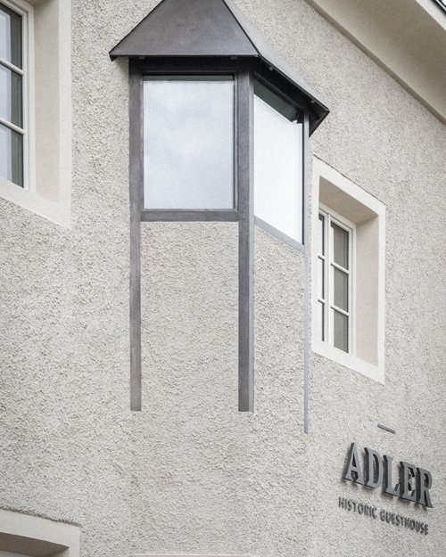 Facciata di un antico guesthouse con finestra a bovindo e scritta Adler