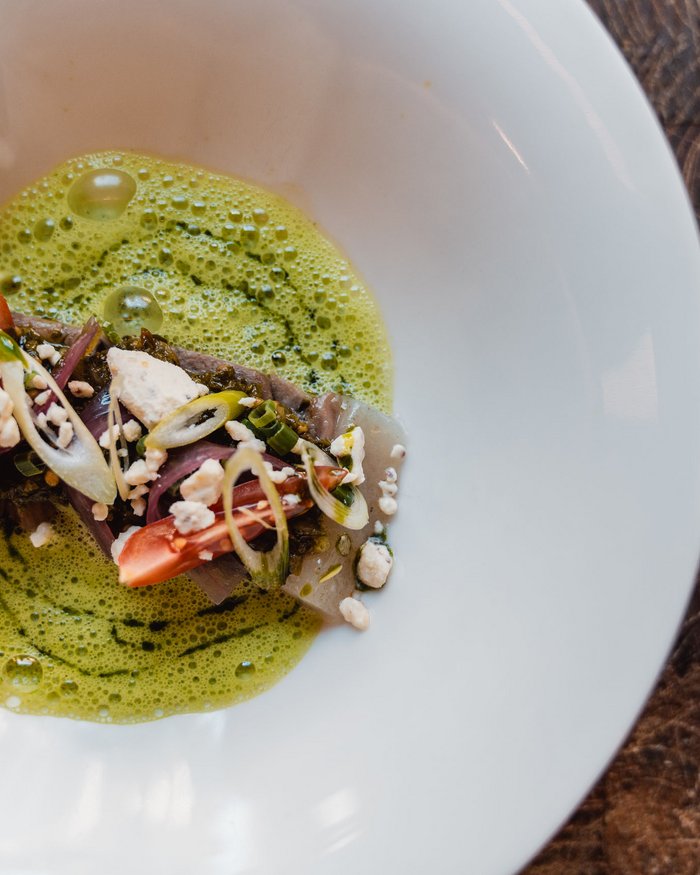 Piatto artistico con pesce, pomodori, salsa verde e guarnizione