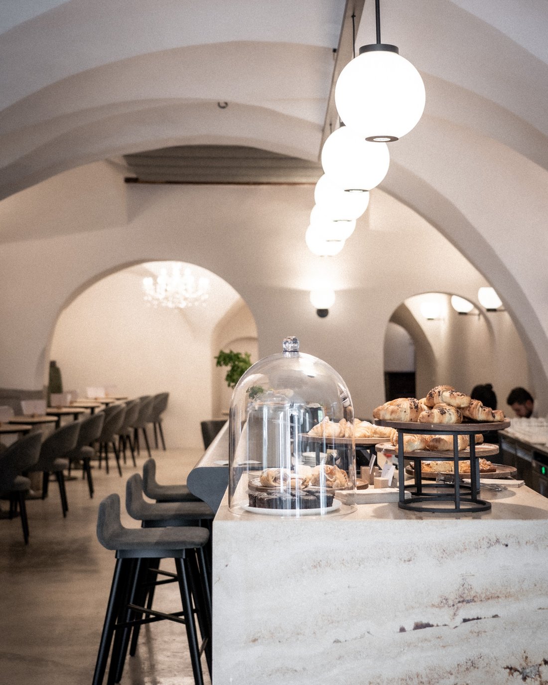 Caffè accogliente con cornetti sul bancone e archi interni moderni