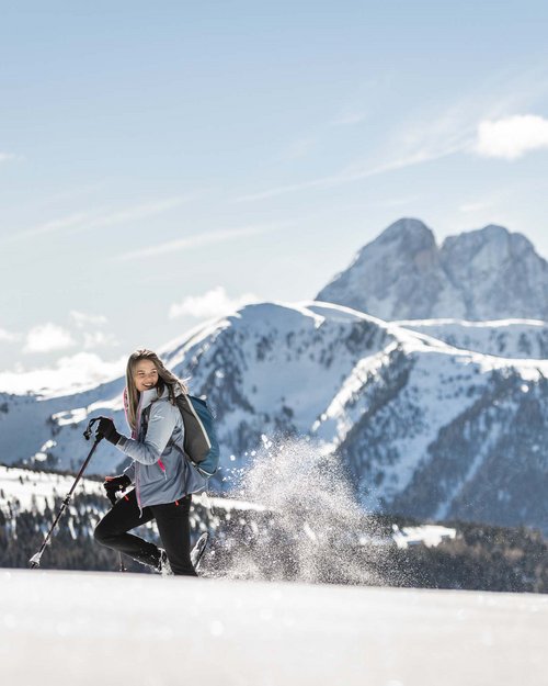 Donna che cammina nella neve con montagne sullo sfondo